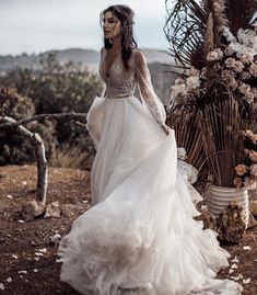 a woman in a wedding dress standing next to a tree with white flowers on it