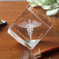 a glass block with a medical symbol on it and a pen sitting next to it