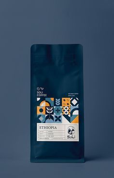 a bag of coffee sitting on top of a blue tablecloth next to a gray wall