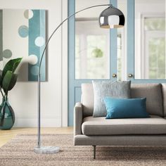 a living room with a couch, chair and floor lamp in front of a blue door