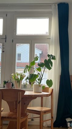 a table and chairs in front of a window with potted plants on the windowsill