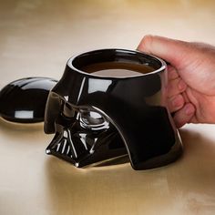 a darth vader coffee mug is being held by a hand