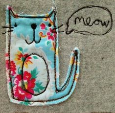 a cat is sitting on the ground next to a piece of fabric that says meow