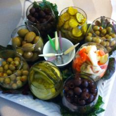 an assortment of olives and pickles on a platter with other food items