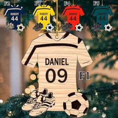 a wooden ornament hanging from a christmas tree with soccer jersey and shoes on it