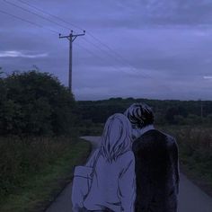 a man and woman walking down a road at night