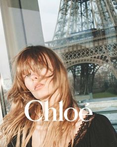 a woman standing in front of the eiffel tower with her hair blowing in the wind