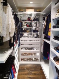 a walk in closet with white shelving and lots of shoes