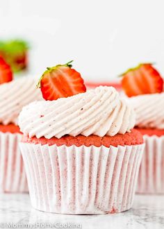 strawberry cupcakes with white frosting and fresh strawberries on top, ready to be eaten