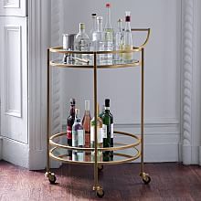 a gold bar cart with bottles and glasses on it