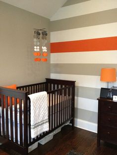 a baby's room is decorated in orange, gray and white