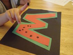 a child is making a letter s craft with construction paper and watermelon slices