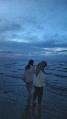 two women walking on the beach at dusk