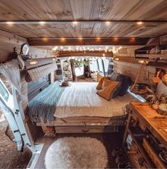 a bed in the middle of a room with wooden walls and ceiling lights hanging above it