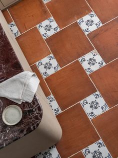 a bathroom with a toilet, sink and tiled flooring in brown and white colors