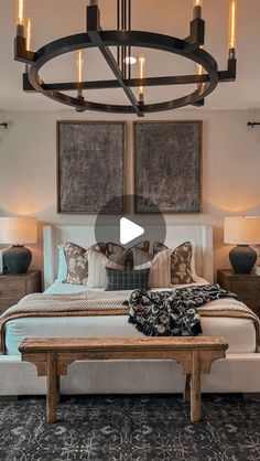 a large bed sitting under a chandelier next to two tables and lamps in a bedroom