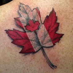 a canadian flag leaf tattoo on the back of a woman's upper back shoulder