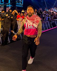 a man is walking in front of a crowd with his hands on his hips and mouth open