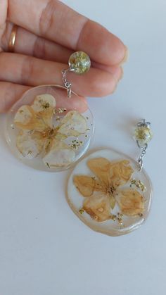 Earrings that hang from resin and inside dried natural flowers. They weigh little and are very comfortable. Diameter 4 cm. 6 cm total length. Unique Flower-shaped Resin Earrings, White Dangle Resin Flower Earrings, Silver Pressed Flower Earrings In Resin, Elegant Resin Earrings With Flower Charm, Silver Pressed Flower Resin Earrings, Silver Resin Earrings With Pressed Flowers, White Resin Dangle Flower Earrings, Handmade Silver Resin Flower Earrings, Handmade Round Resin Flower Earrings