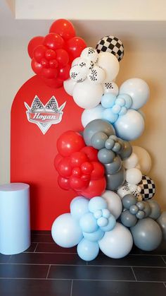 balloons and streamers are on the floor next to a red gas pump with black and white checkered flags