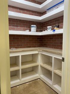 an empty pantry with brick walls and shelves