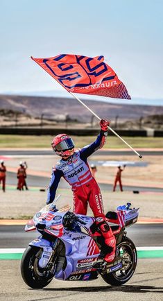 a man riding on the back of a motorcycle holding a flag