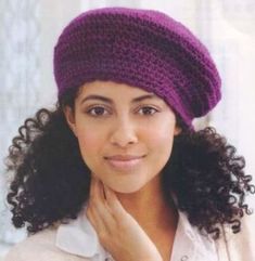 a woman wearing a purple knitted hat and posing for the camera with her hand on her chin