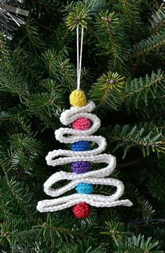 a crocheted christmas tree ornament hanging from a pine tree