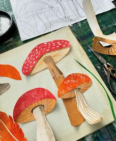 paper mushrooms are cut out and placed on a piece of crafting paper with scissors