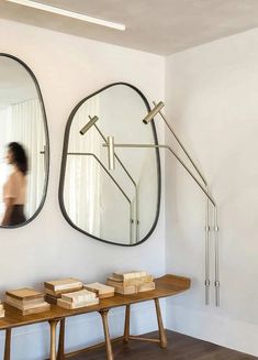 a woman is walking past two mirrors on the wall