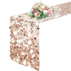 the table runner is decorated with pink flowers and sequins, along with greenery