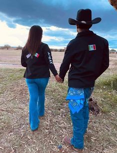 a man and woman holding hands while walking in the grass