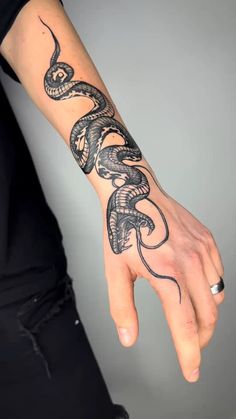 a hand with a snake tattoo on it