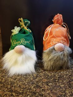 two small stuffed animals wearing hats on top of a counter next to an orange and green bag