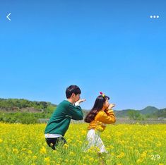 two children are standing in a field with yellow flowers and one child is looking up at the sky