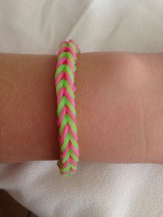 a woman's arm with a pink and green braid bracelet on top of it