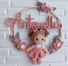 a crocheted doll hanging on the wall with name attached to it's frame