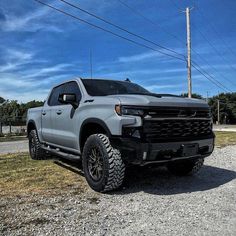 a silver truck parked on top of a gravel road