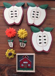 there are some decorations made to look like apples and flowers on the wooden table next to each other