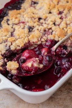 blueberry cobbler in a white baking dish with a spoon resting on the top