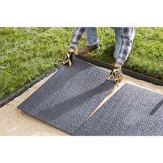 a pair of hands holding two pliers on top of a door mat in the grass