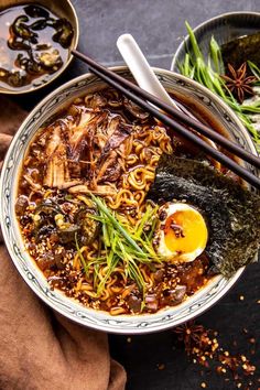 two bowls filled with noodles, carrots and an egg on the side next to chopsticks