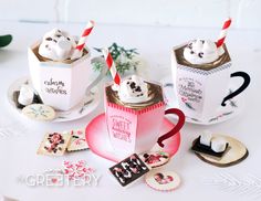 two cups filled with ice cream sitting on top of a table next to cookies and marshmallows