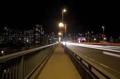 the city lights shine brightly in the night sky as traffic passes by on a bridge