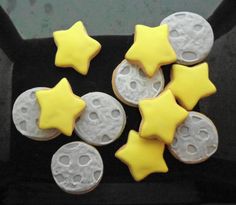 some yellow and white decorated cookies in a black box with holes on the top one is shaped like moon and stars