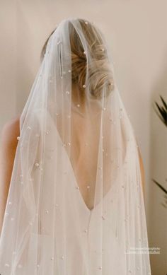 a woman wearing a wedding veil with pearls on it