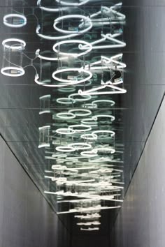 an abstract sculpture is shown in the middle of a hallway with lights hanging from it's sides