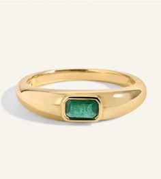 a gold ring with an emerald stone in the center and a thin band around it