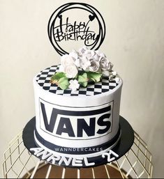 a black and white cake with flowers on top is sitting on a wire rack in front of a wall