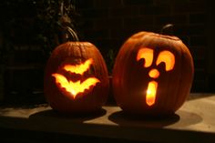 two carved pumpkins sitting on top of a window sill with faces carved into them